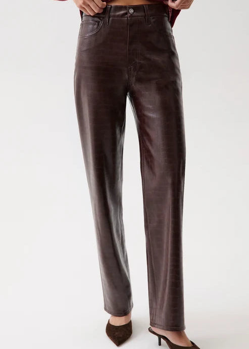 A person wearing dark brown faux-leather straight-leg pants, styled with a burgundy crop top and brown pointed-toe mule heels, photographed against a clean white studio background.