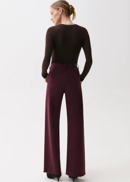 A woman shown from the back wearing a dark brown long-sleeve top and deep burgundy wide-leg trousers against a plain white studio background.