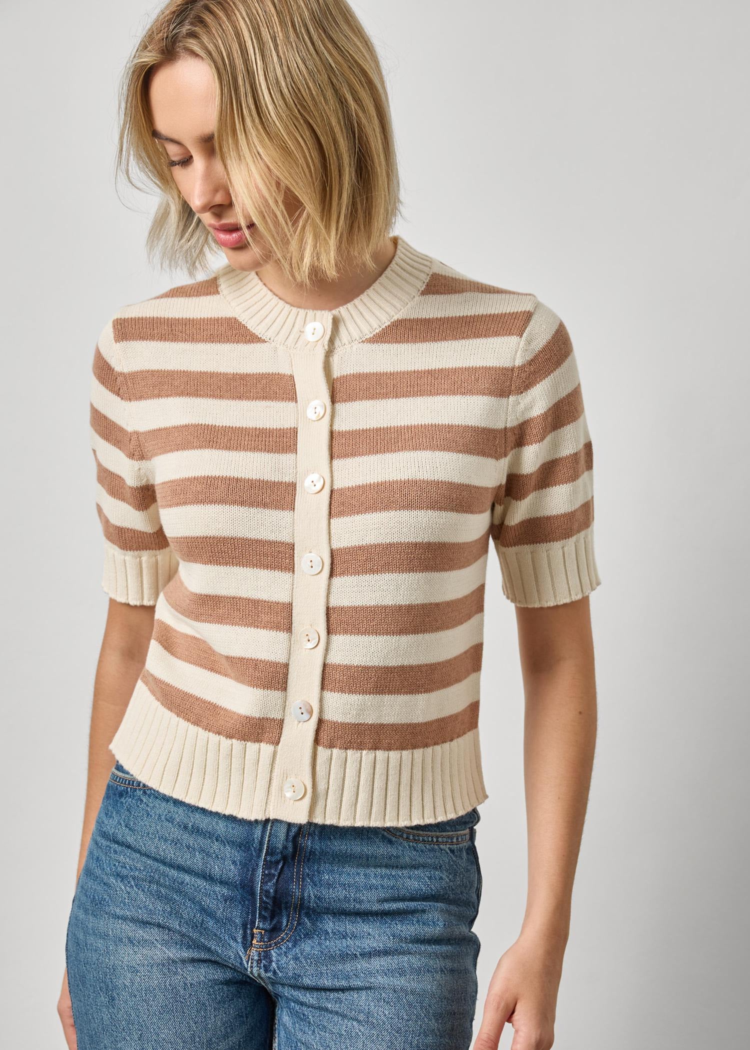 Woman wearing a striped sweater and jeans on a plain background