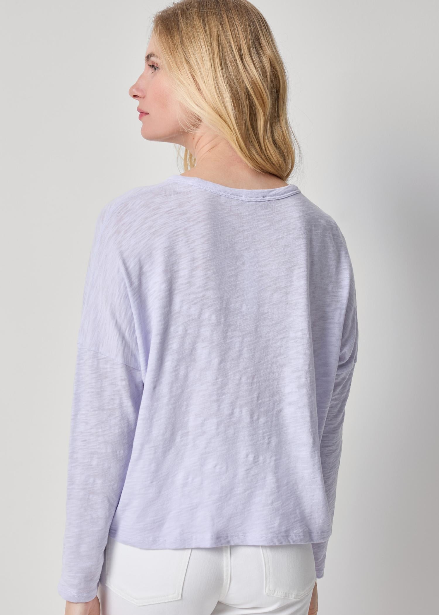 Woman wearing a light purple long-sleeve top against a plain background