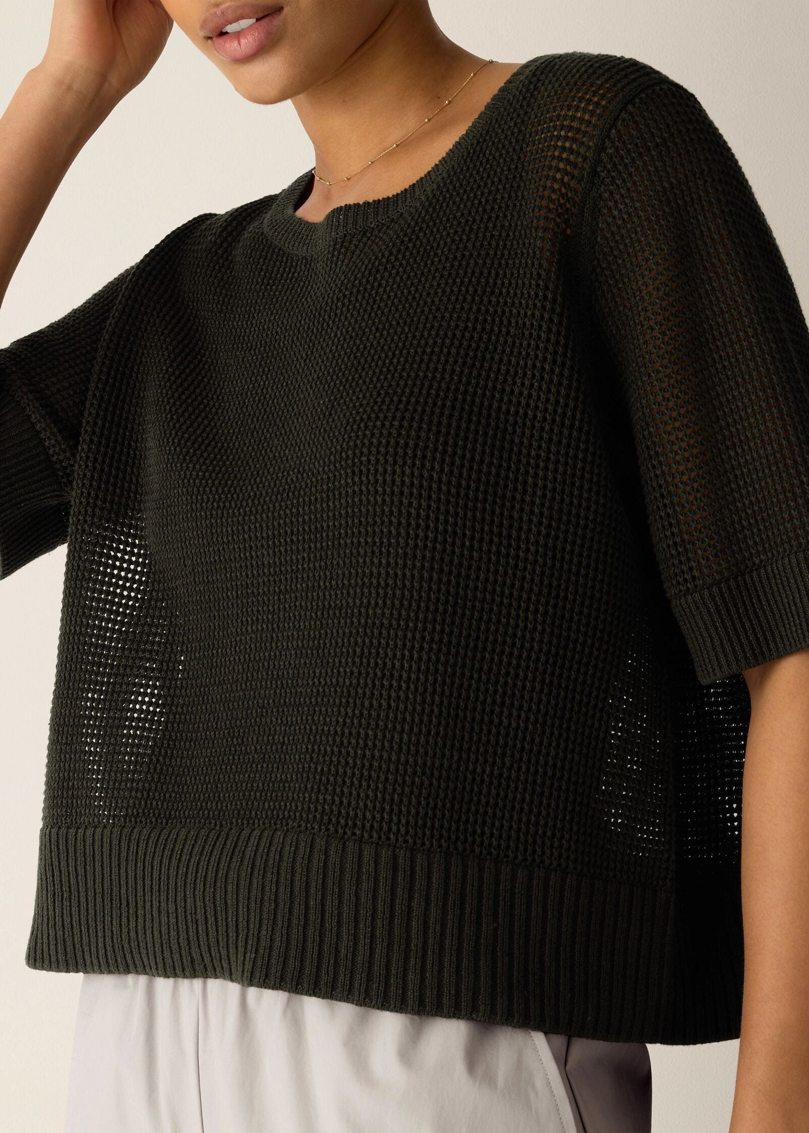 Black textured sweater worn by a person on a neutral background