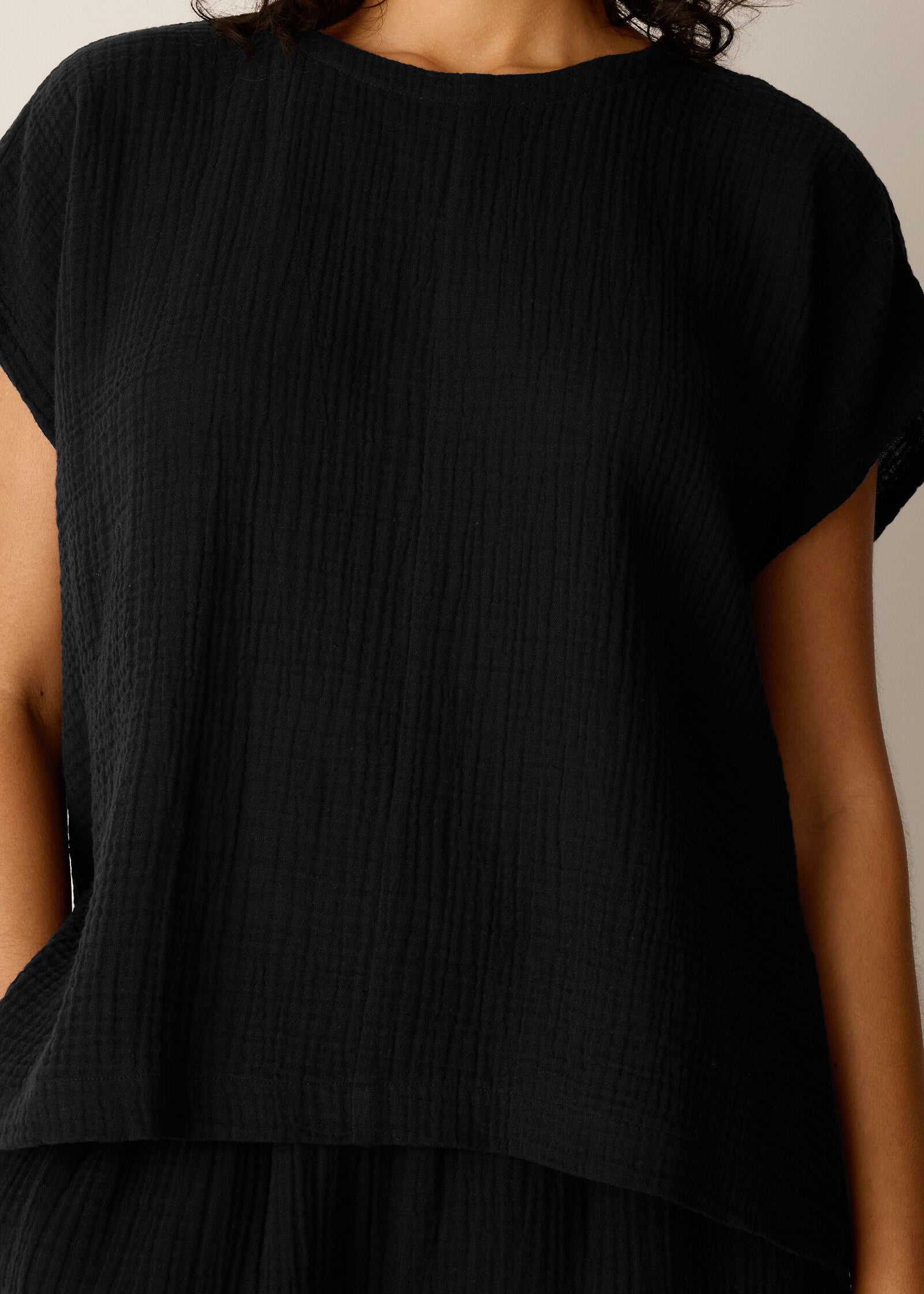 Person wearing a black textured top against a neutral background