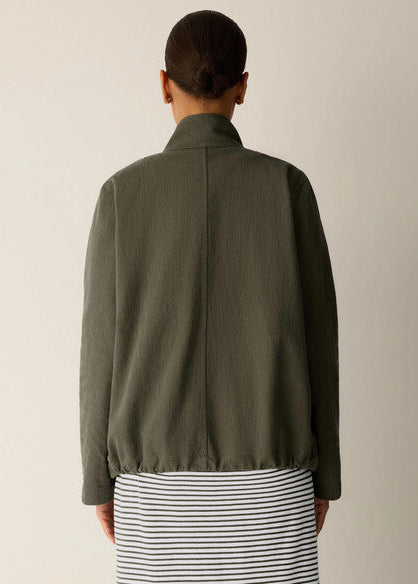 Person wearing a green jacket with a neutral background