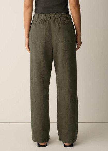 Person wearing olive green pants on a beige background