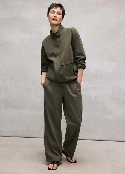 Person wearing a green outfit against a plain background