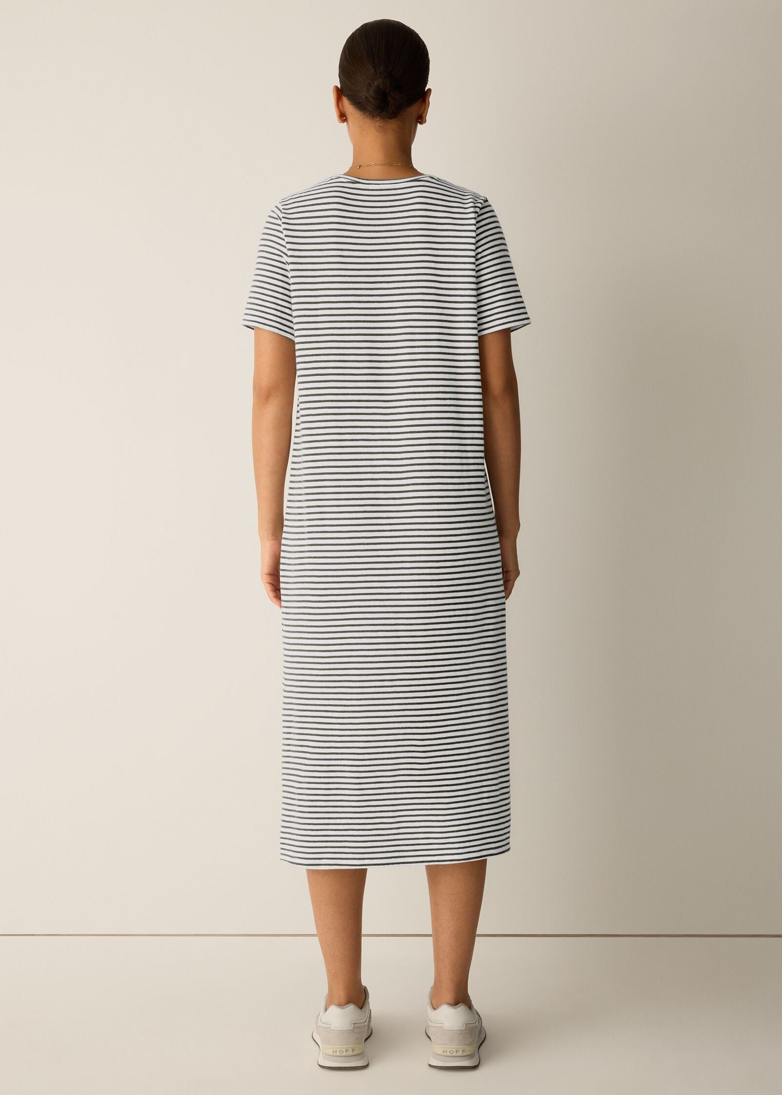 Person wearing a striped dress against a plain background