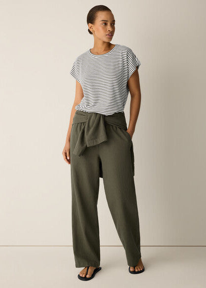 Woman wearing a striped shirt and olive green pants on a plain background