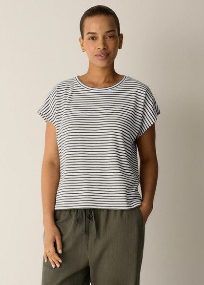 Woman wearing a black and white striped shirt with green pants on a beige background