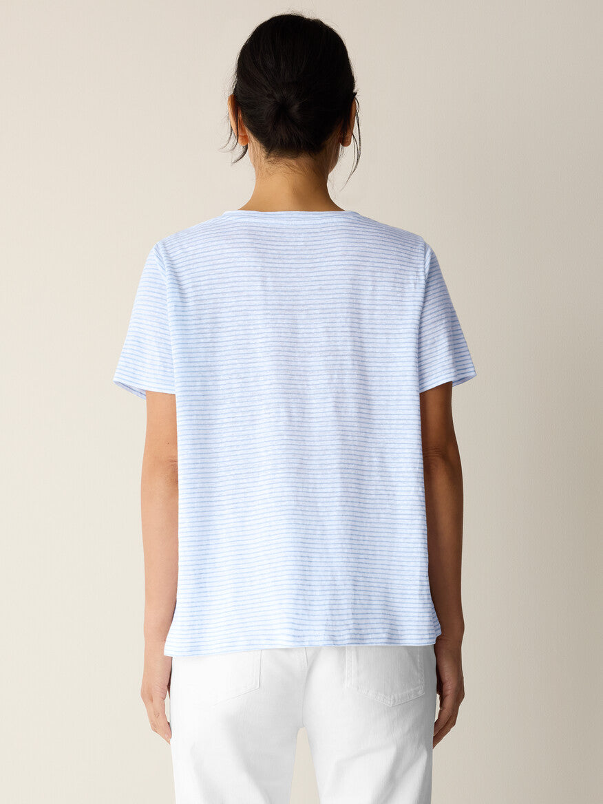 Person wearing a light blue striped t-shirt on a beige background