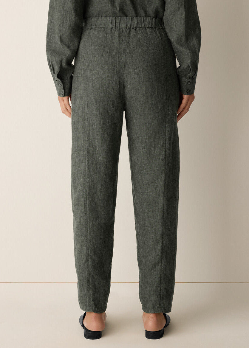 Person wearing dark gray pants and a matching top on a beige background