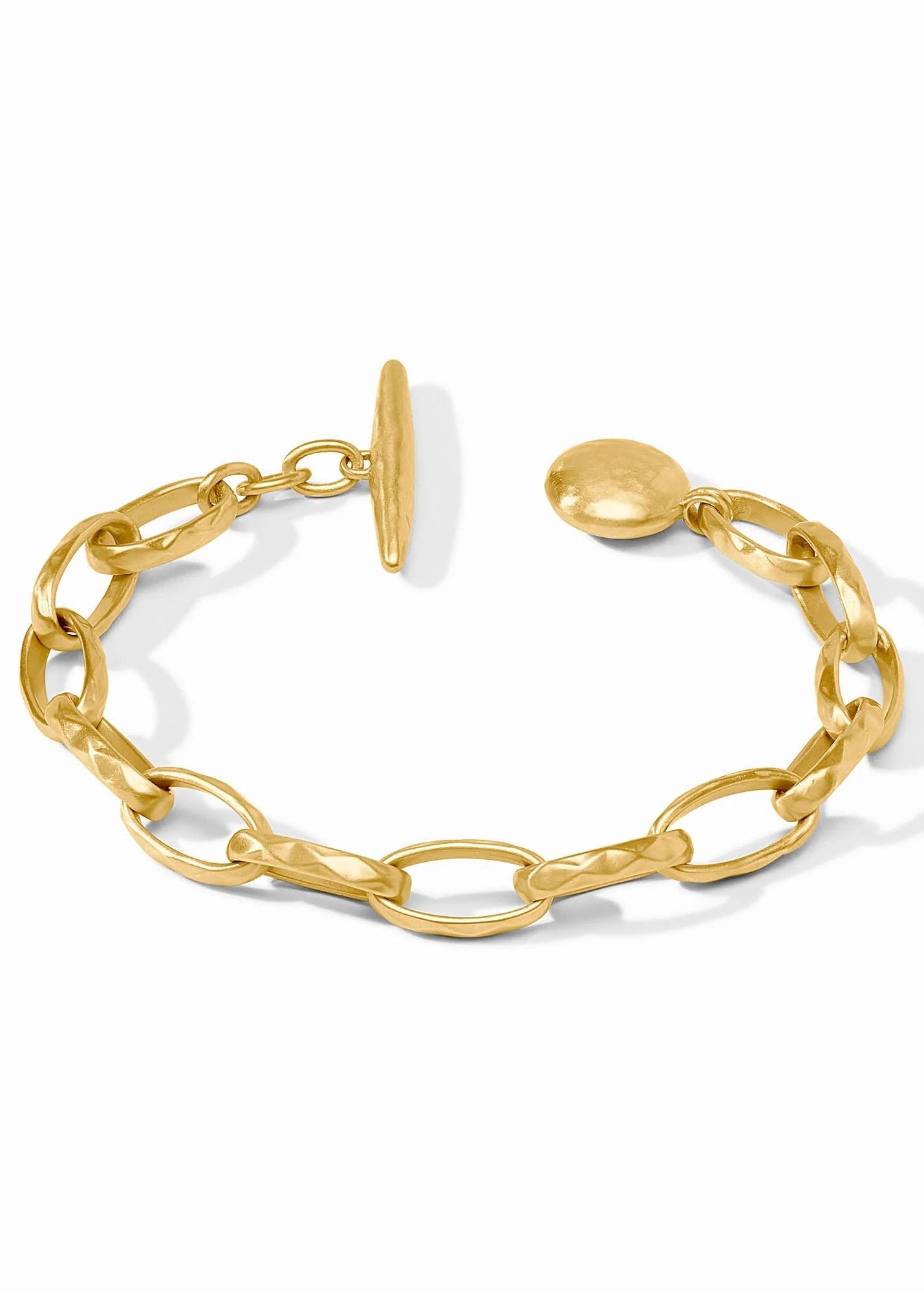 A gold chain link bracelet with a flat bar clasp and a small round tag, displayed on a clean white background.
