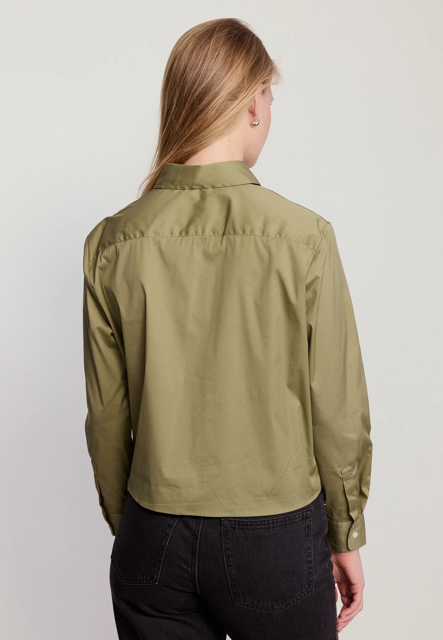 Person wearing a green jacket on a plain background