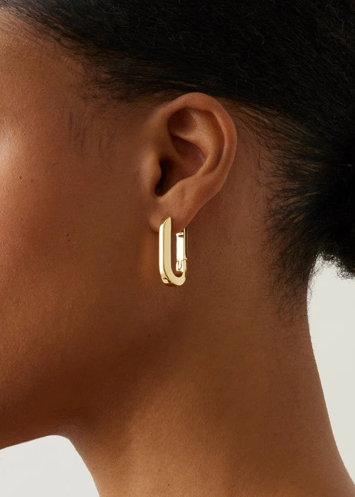 Gold hoop earring worn by a person with a neutral background