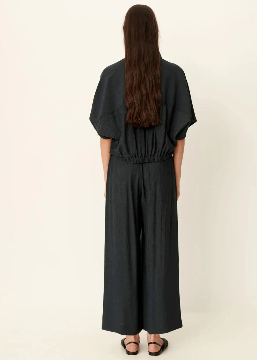 Person wearing a black jumpsuit on a plain background