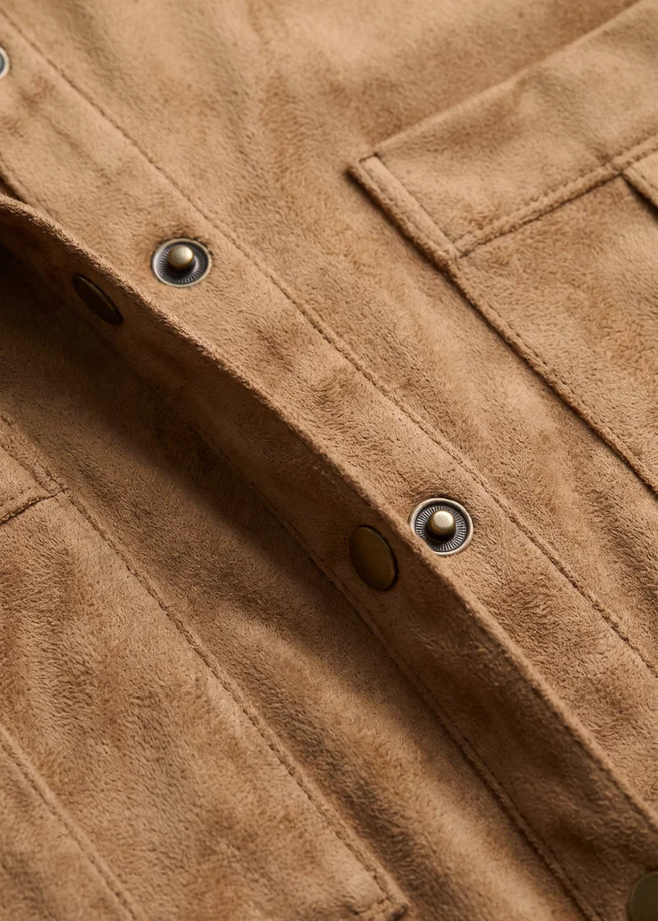 Close-up of a brown suede or nubuck jacket fabric with metal snap buttons and a pocket detail.