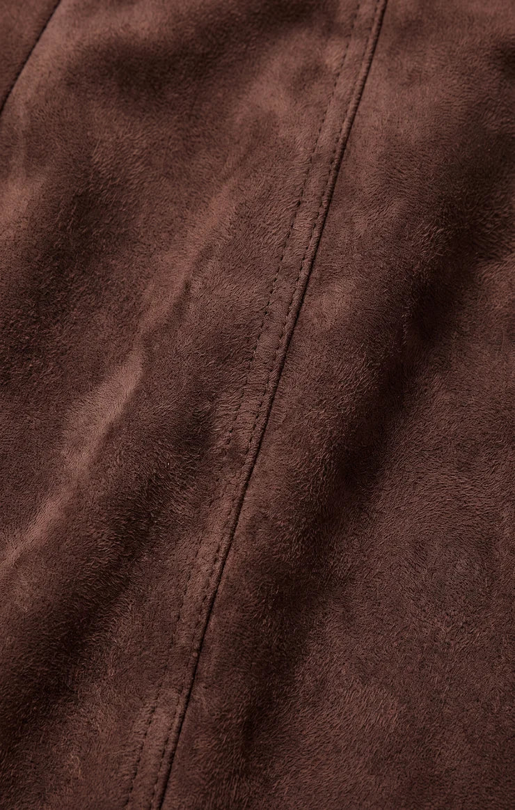 Close-up of a brown suede or microfiber fabric with a visible center seam and stitched texture.