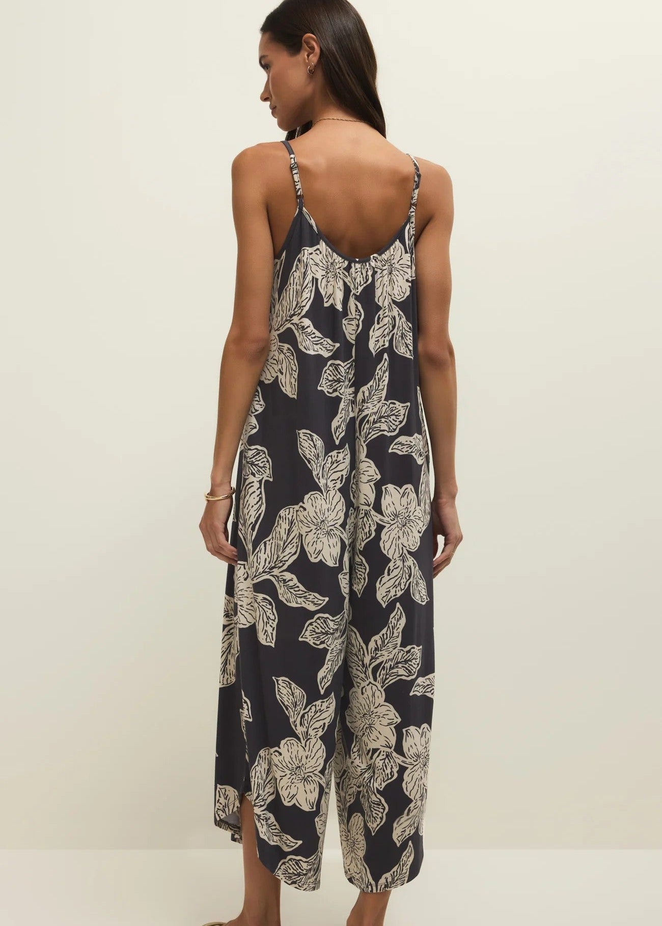 Woman wearing a floral jumpsuit on a plain background