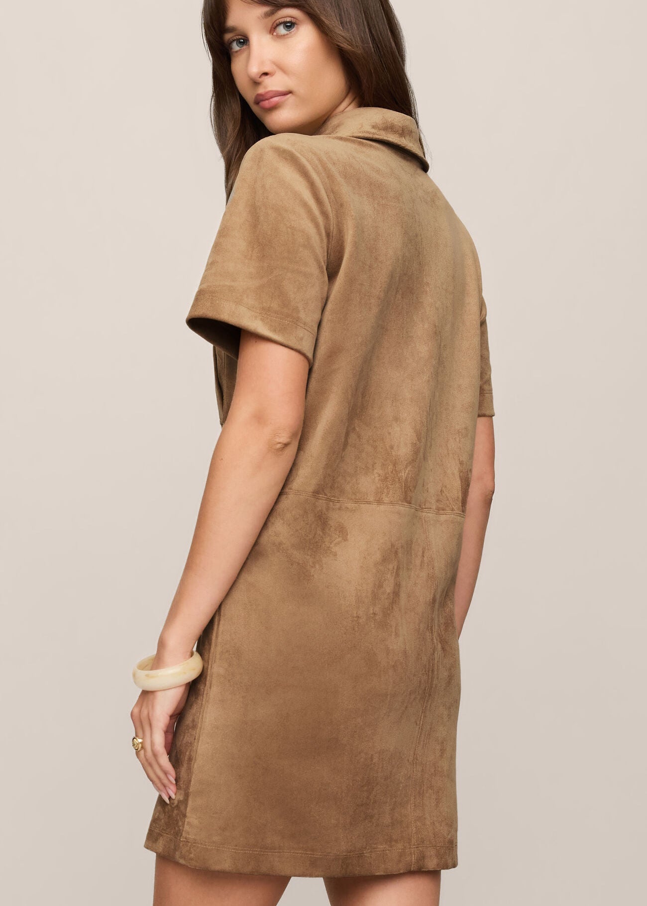 Woman wearing a brown suede dress against a plain background