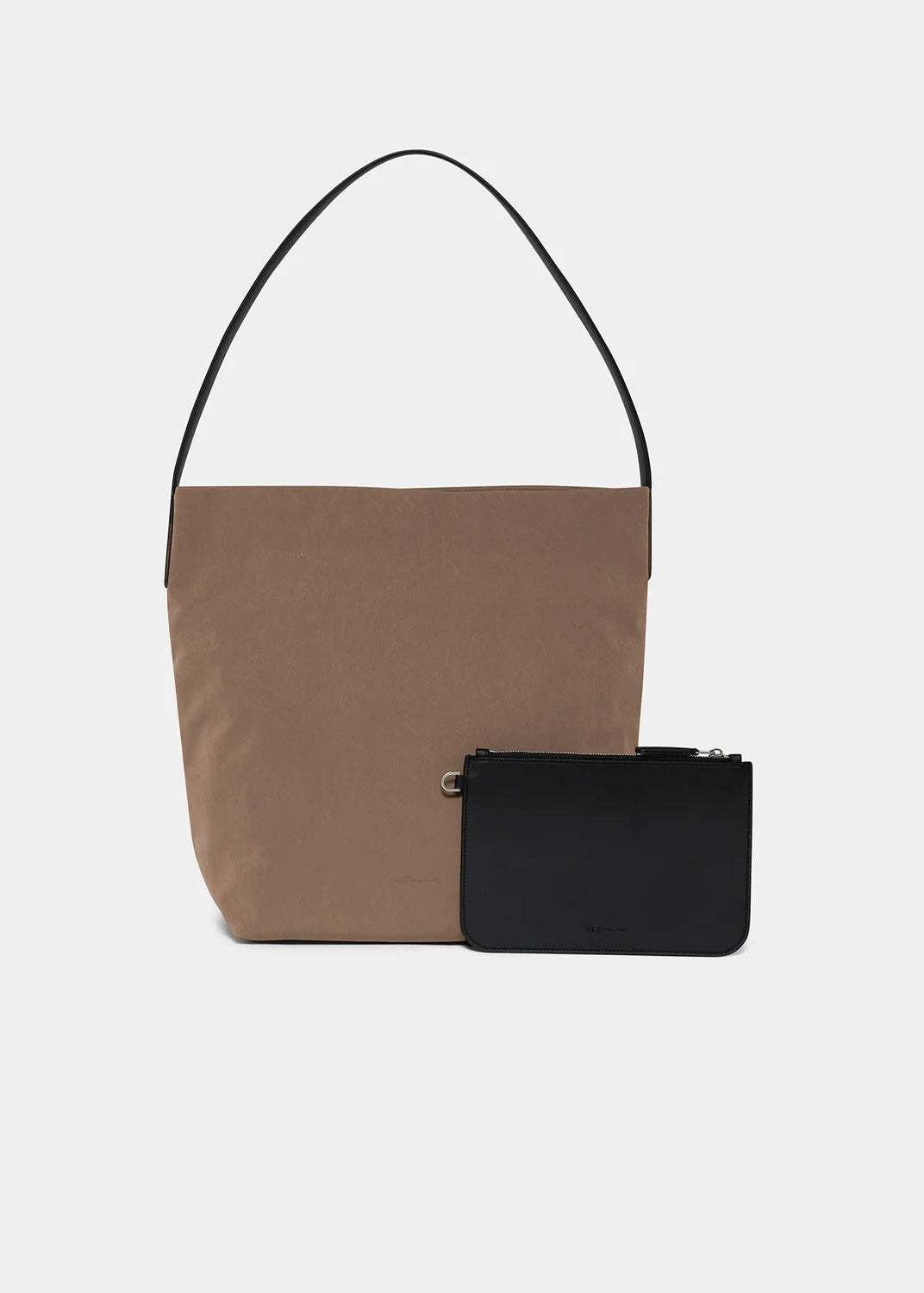 A minimalist color-blocked tote bag in brown and black with a single thin shoulder strap, shown alongside a small black zip pouch on a light gray background.