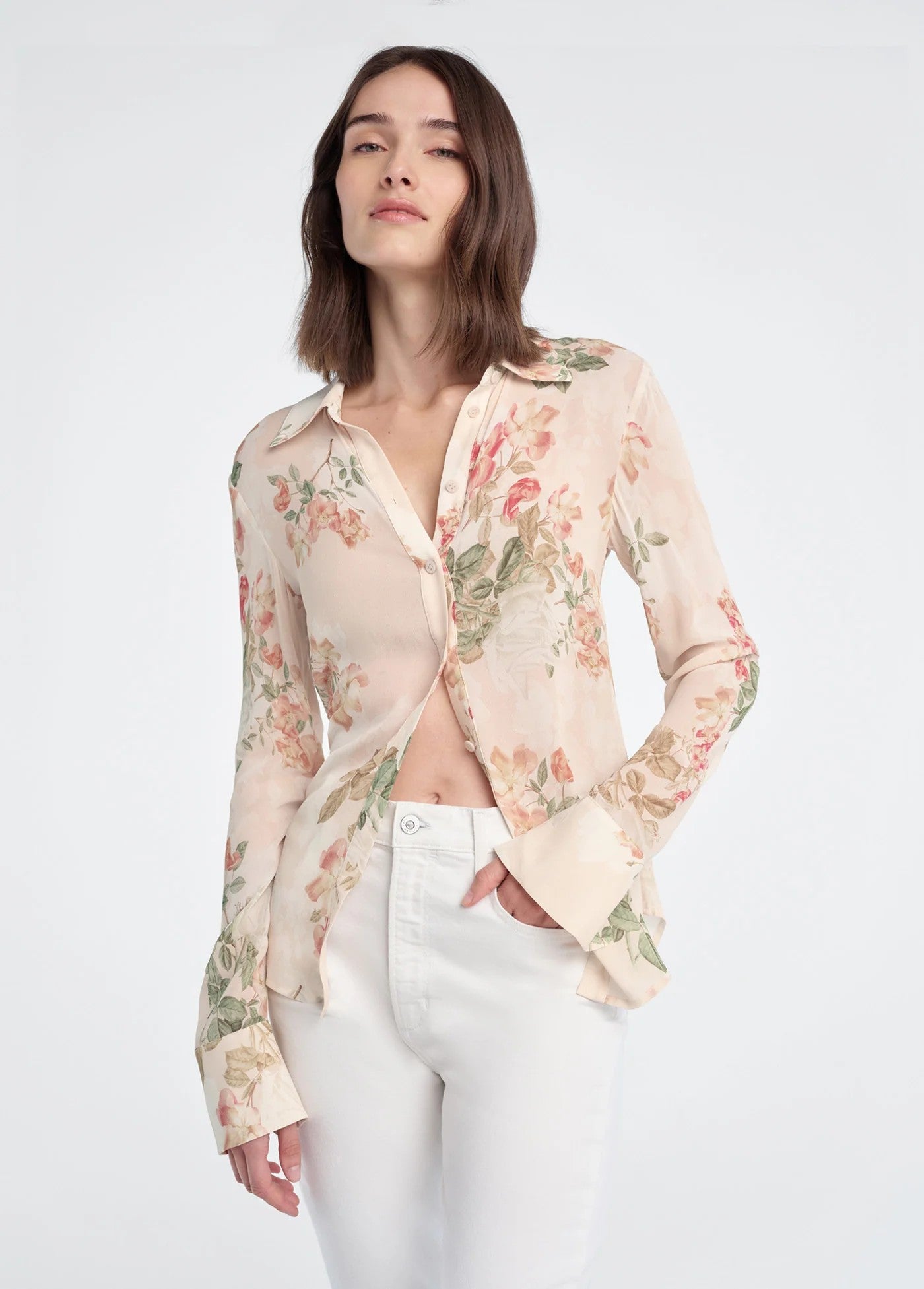 Woman wearing a floral blouse and white pants on a white background