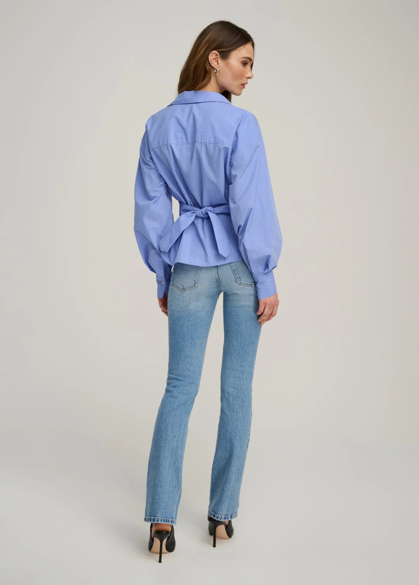 Woman wearing a blue shirt and jeans on a plain background