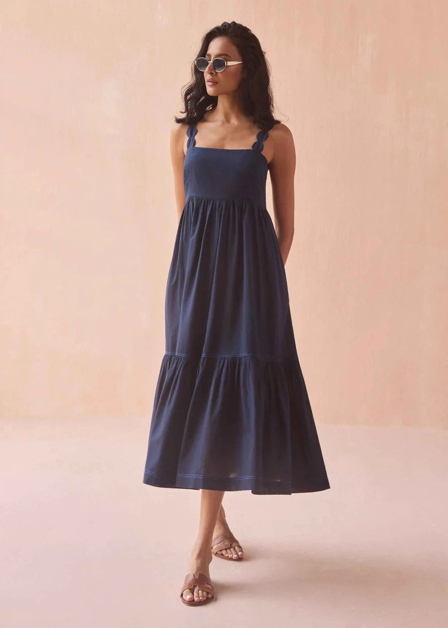 Woman wearing a navy blue dress against a beige background