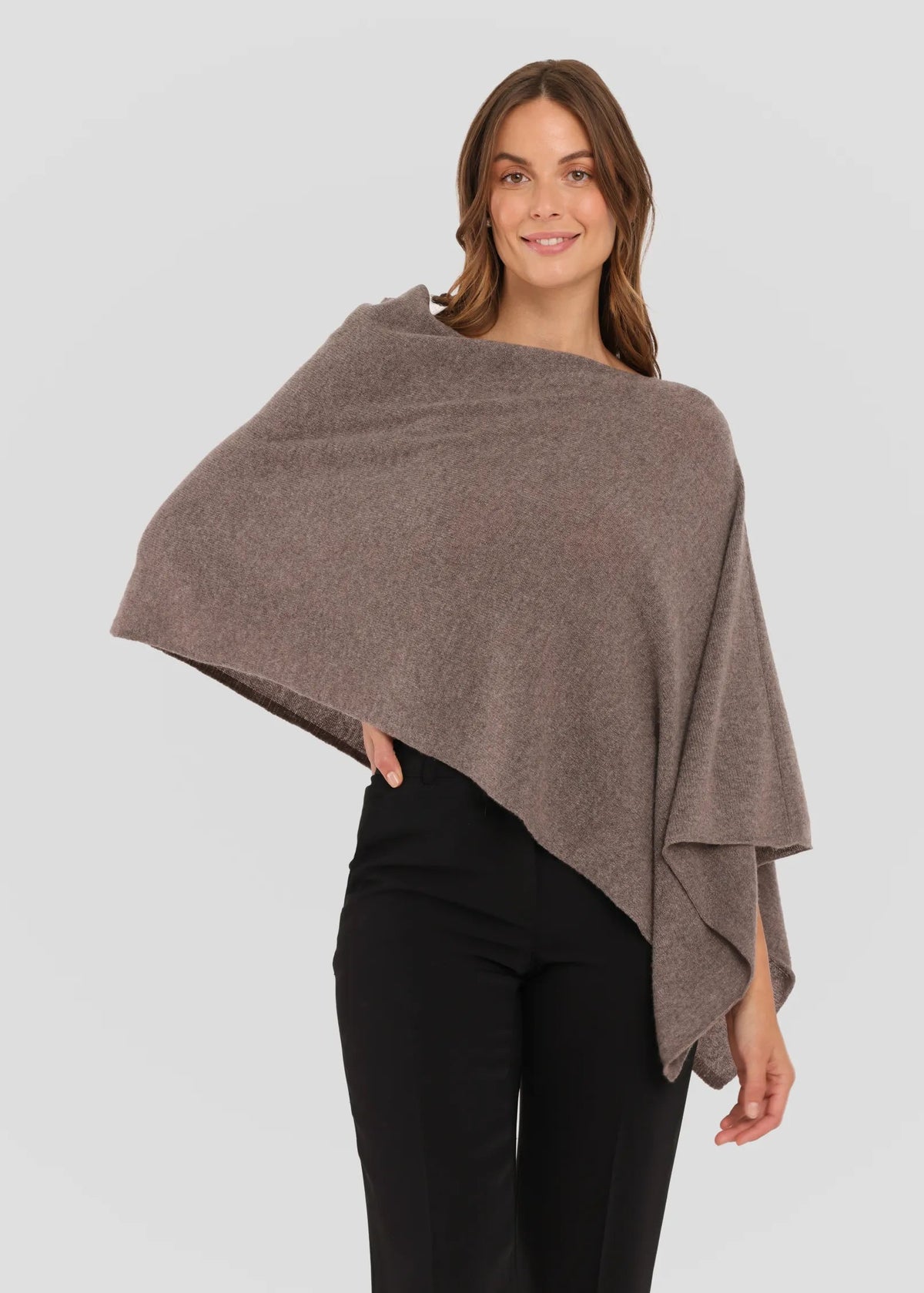 Woman wearing a brown poncho against a plain background