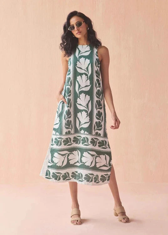 Woman wearing a green and white patterned dress against a pink background