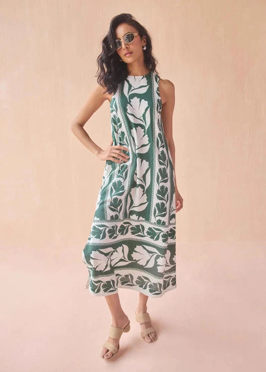 Woman wearing a green and white patterned dress on a pink background