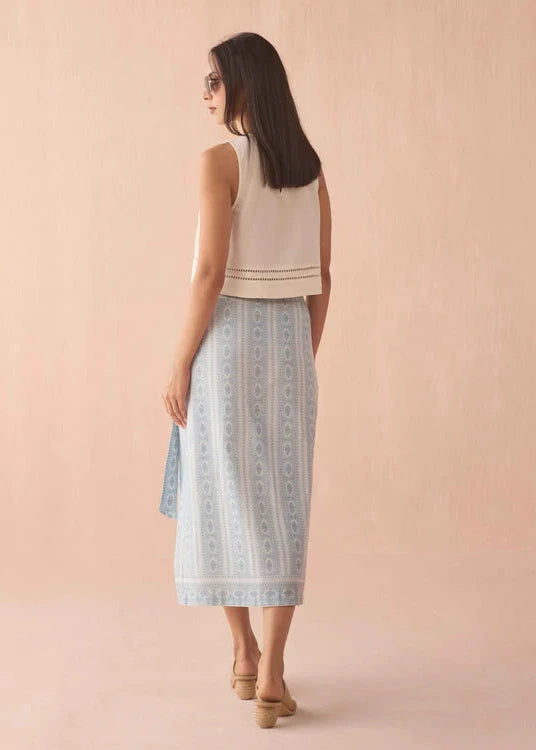 Woman wearing a sleeveless top and patterned skirt on a pink background