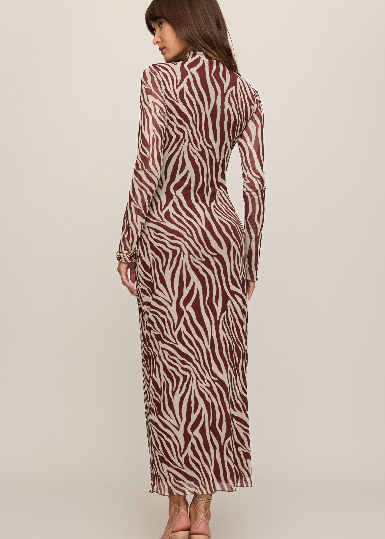 Woman wearing a zebra print dress on a plain background