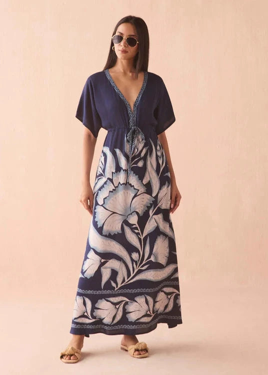 Woman wearing a navy blue and white floral patterned dress on a beige background