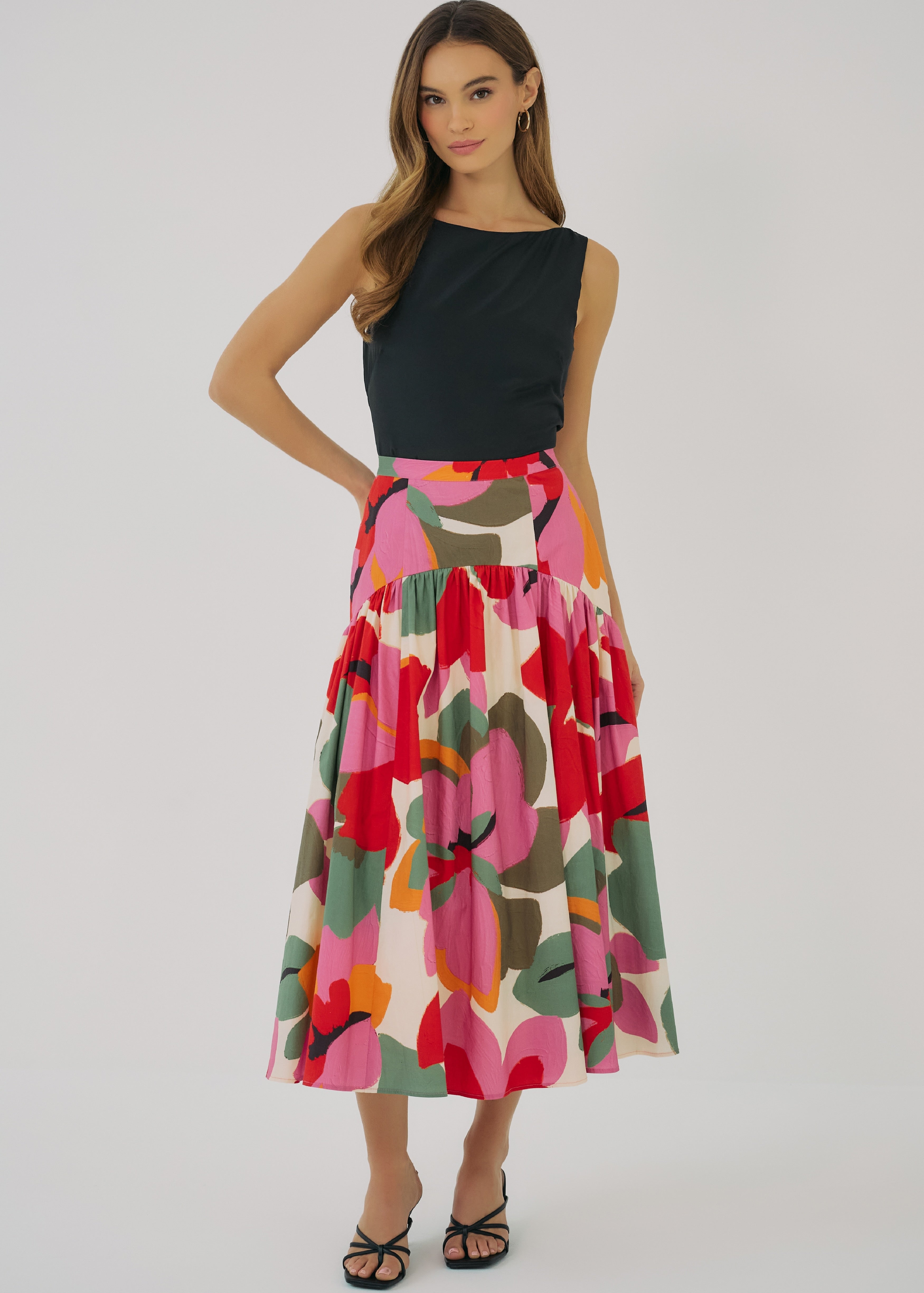 Woman wearing a black top and colorful floral skirt on a white background