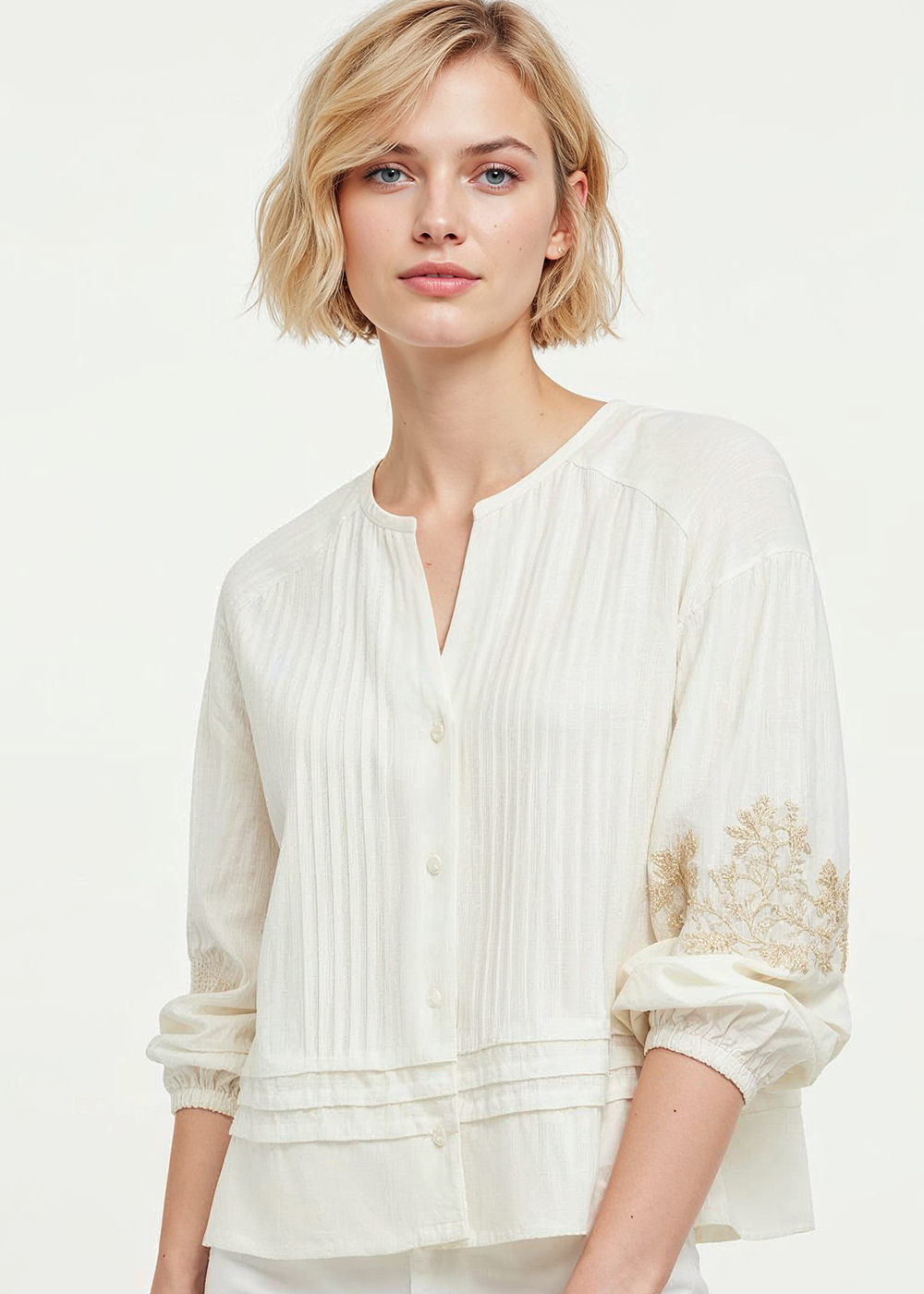 Woman wearing a white blouse with floral embroidery on a white background