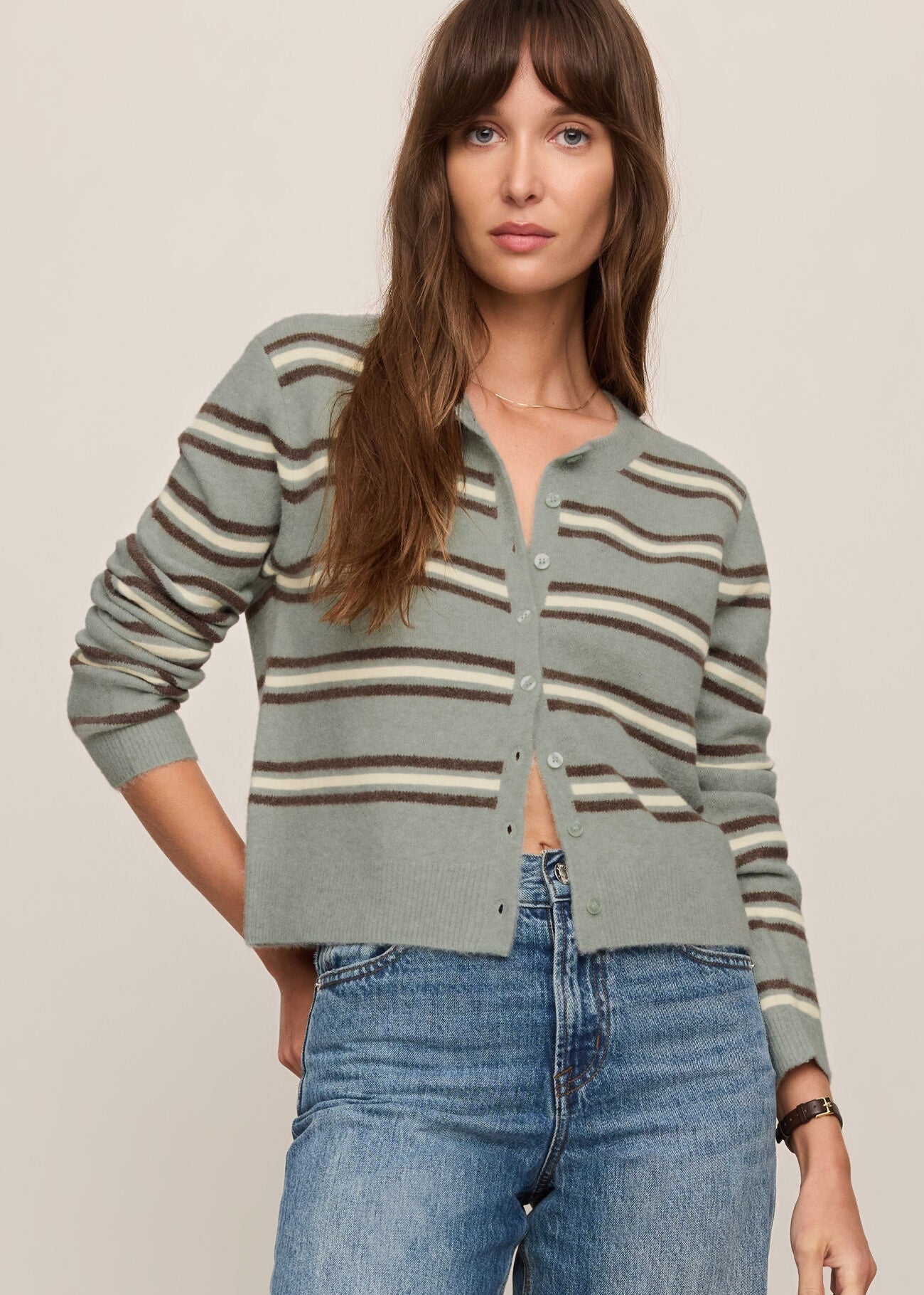 Woman wearing a striped sweater and jeans against a plain background