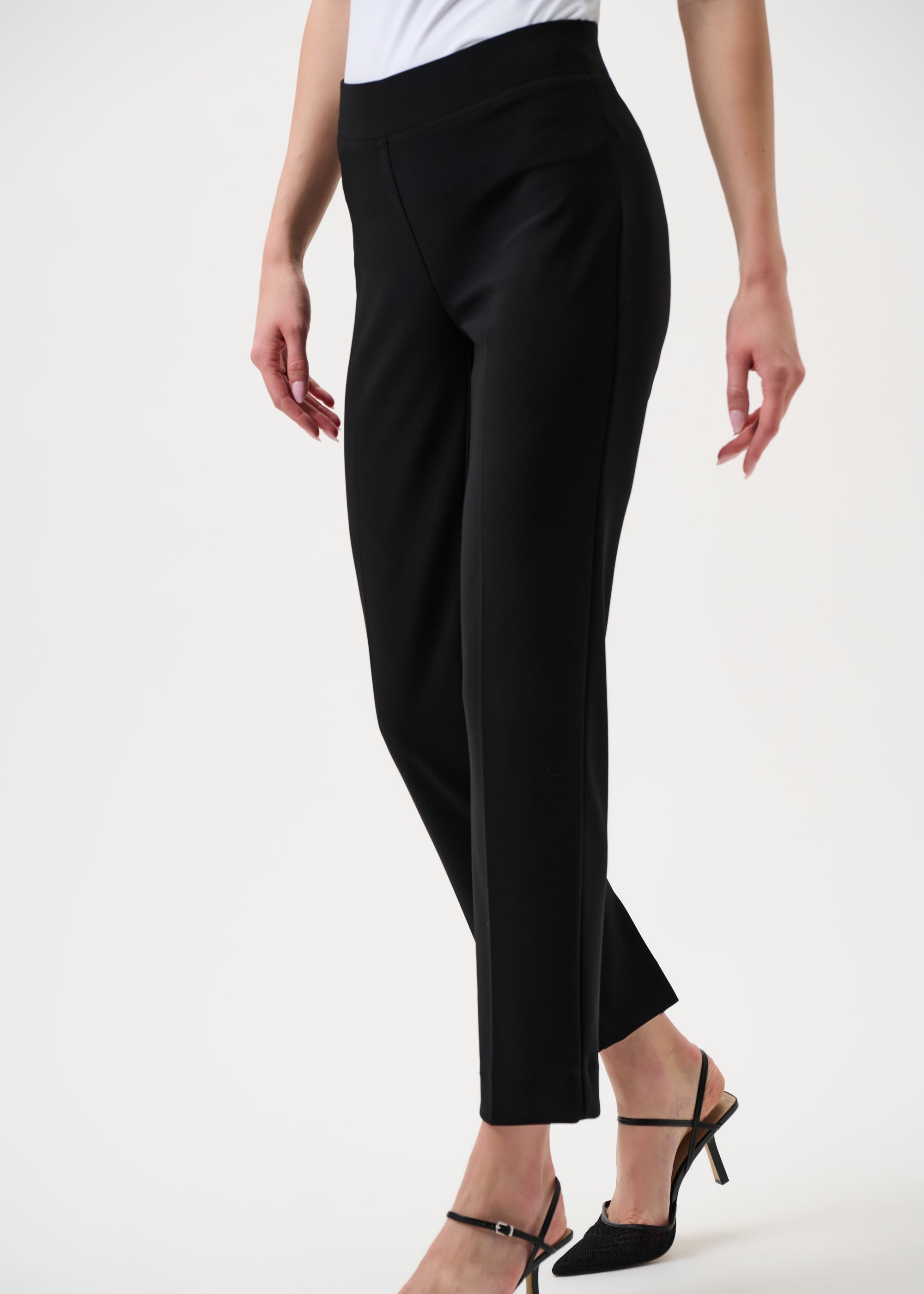 Person wearing black pants and black high heels on a white background