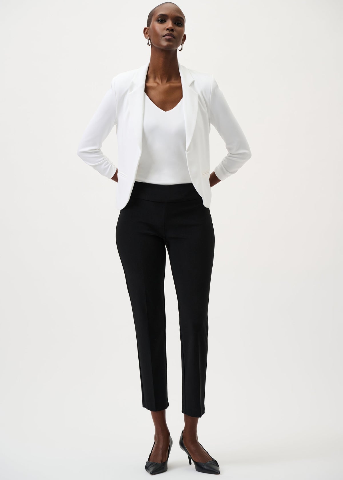 Woman wearing a white blazer and black pants on a white background
