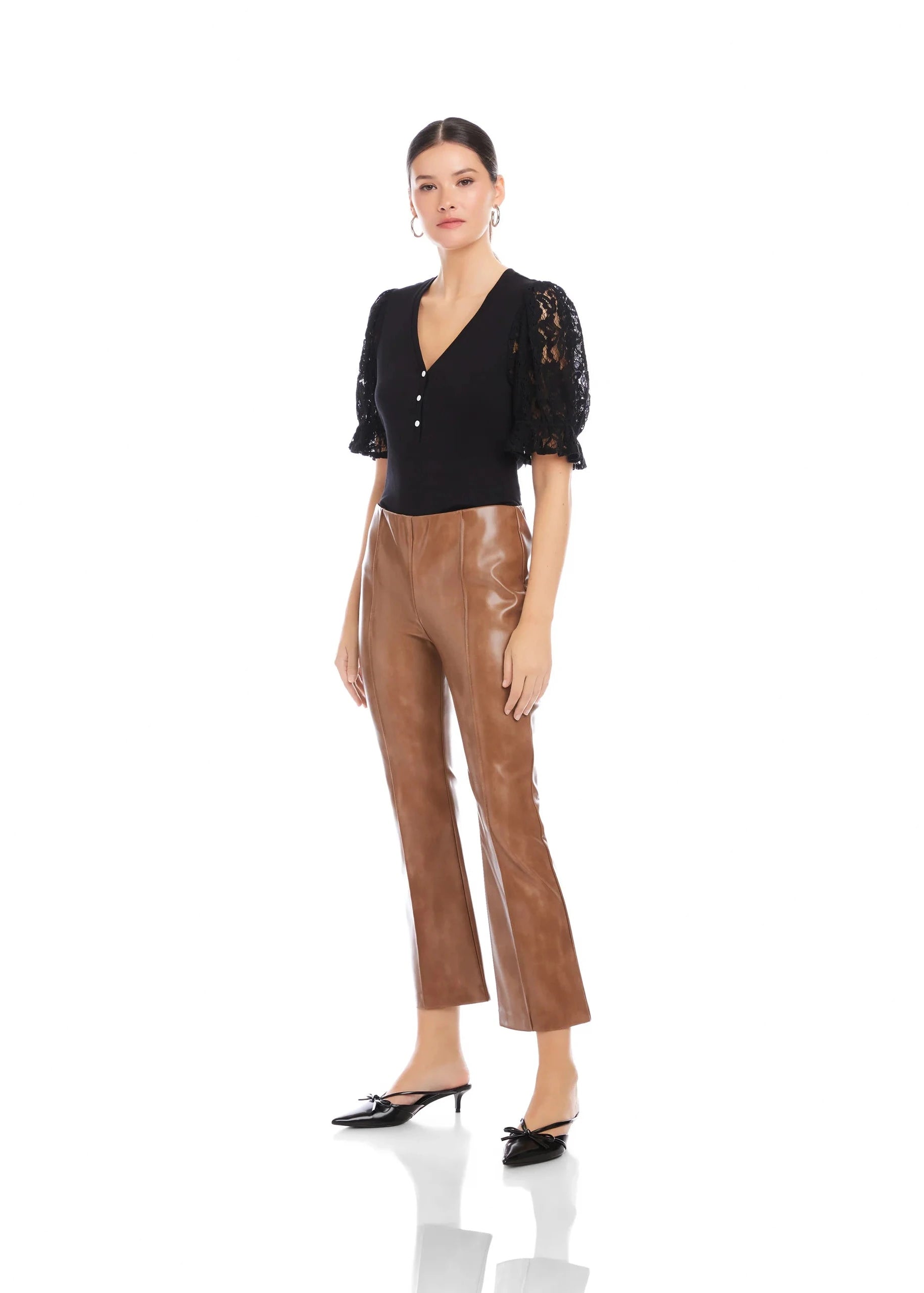 Woman wearing a black lace top and brown leather pants on a white background