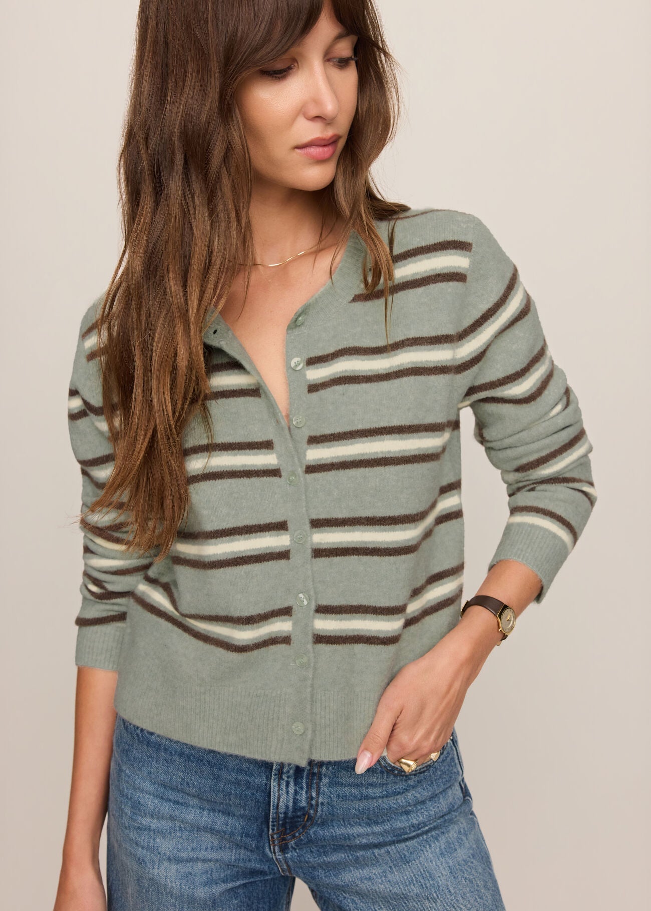Woman wearing a striped sweater and jeans against a neutral background