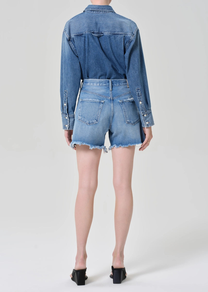 Person wearing a denim jacket and shorts on a white background