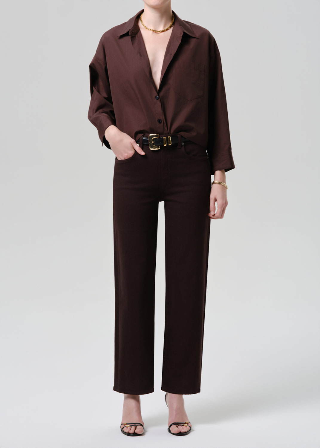 Person wearing a brown outfit with a belt on a white background