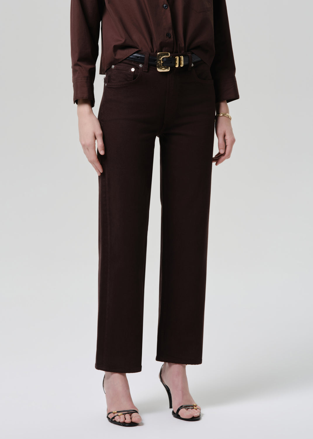 Person wearing a brown outfit with a belt on a white background