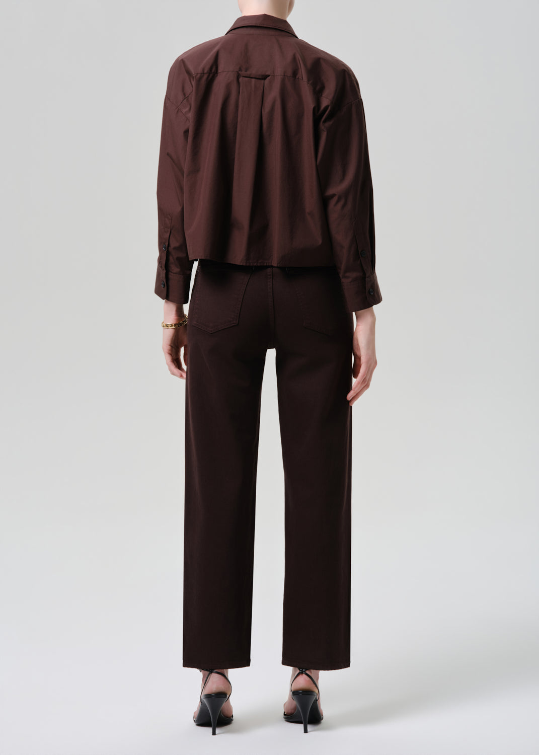 Person wearing a brown shirt and pants on a plain background