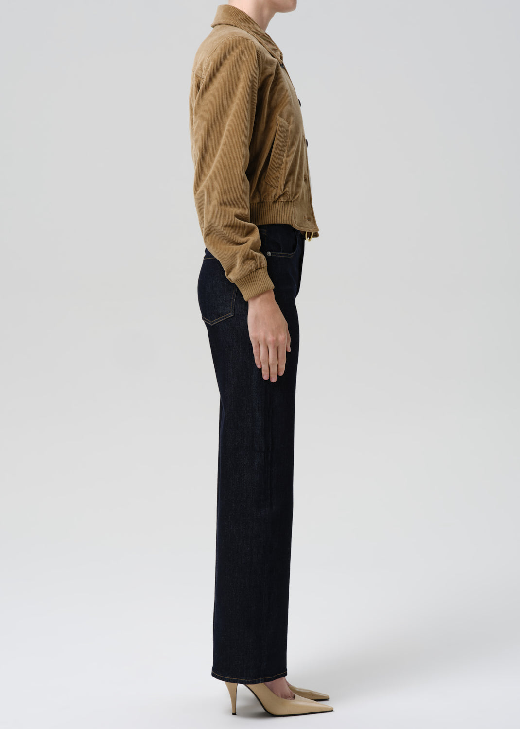 Person wearing a brown jacket and black pants on a white background