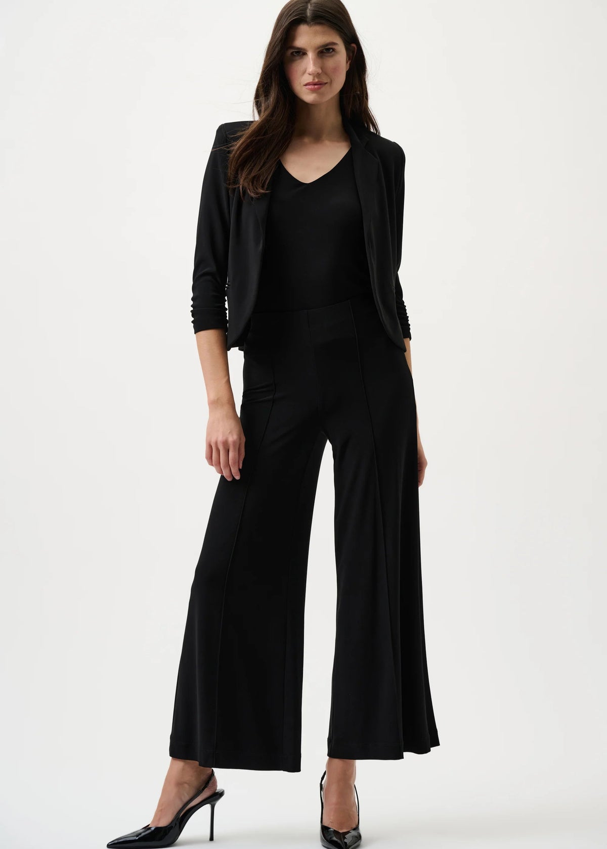 Woman wearing a black outfit with wide-leg pants on a white background