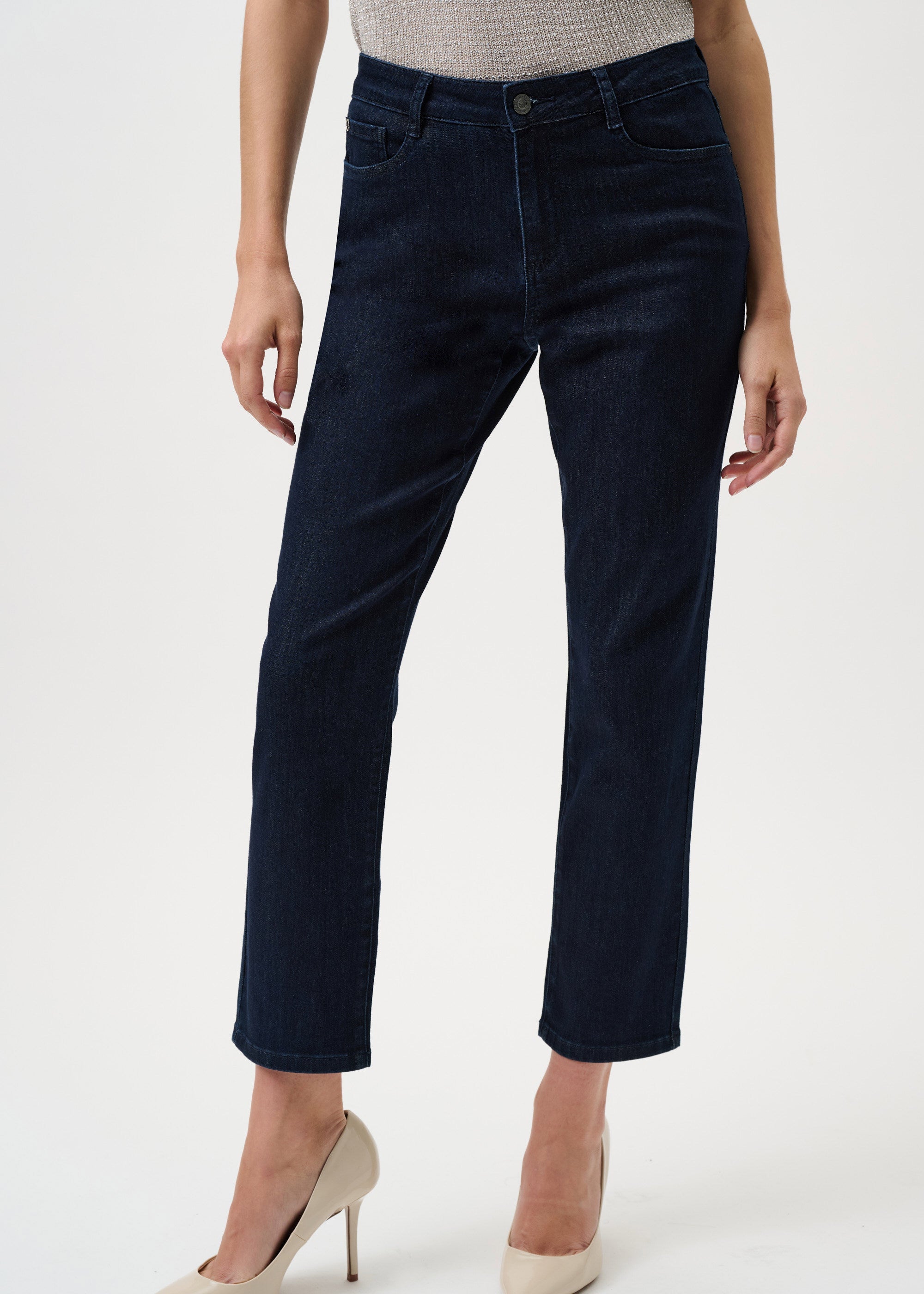 Person wearing dark blue jeans and beige heels on a white background