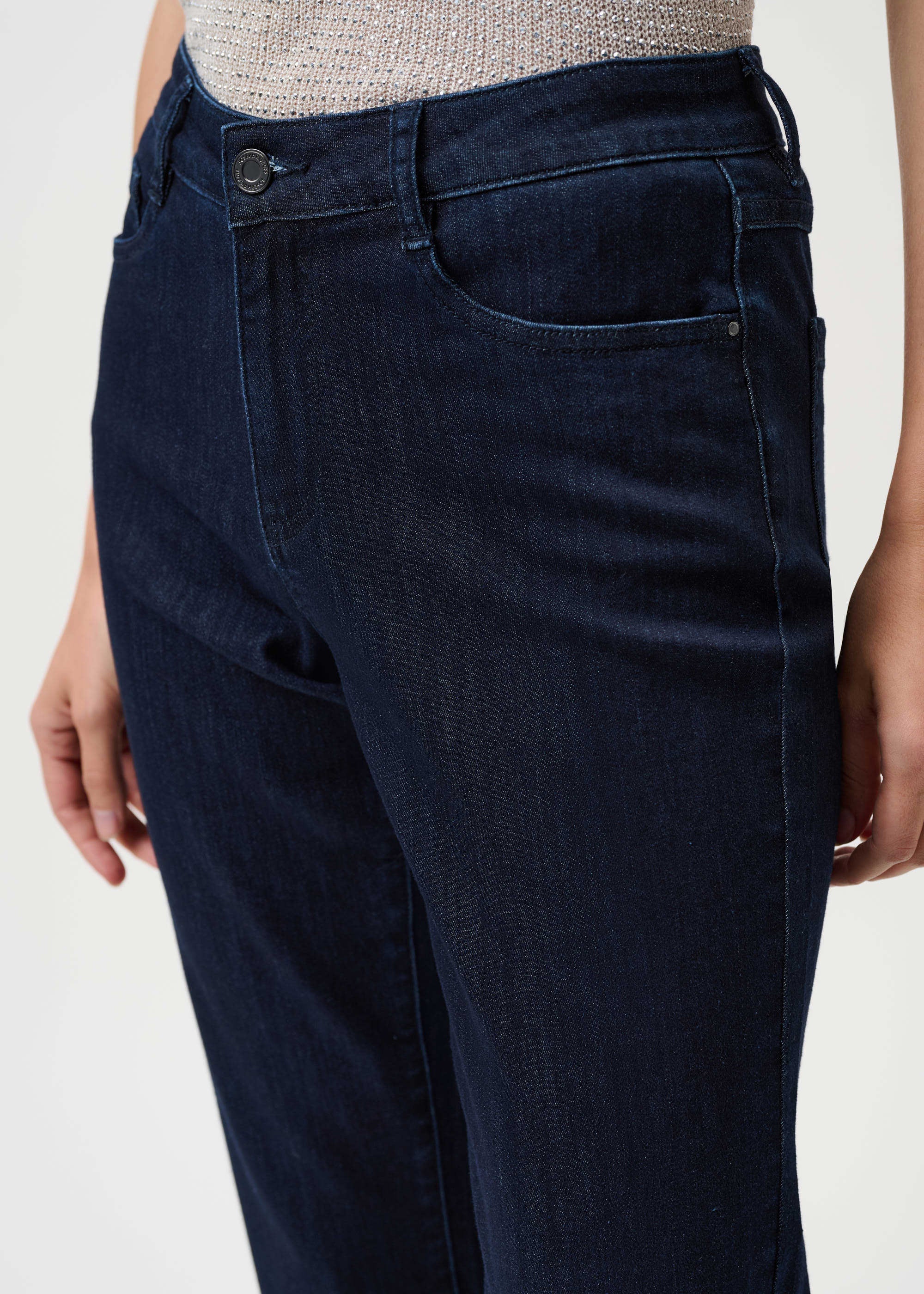 Dark blue jeans worn by a person on a light gray background