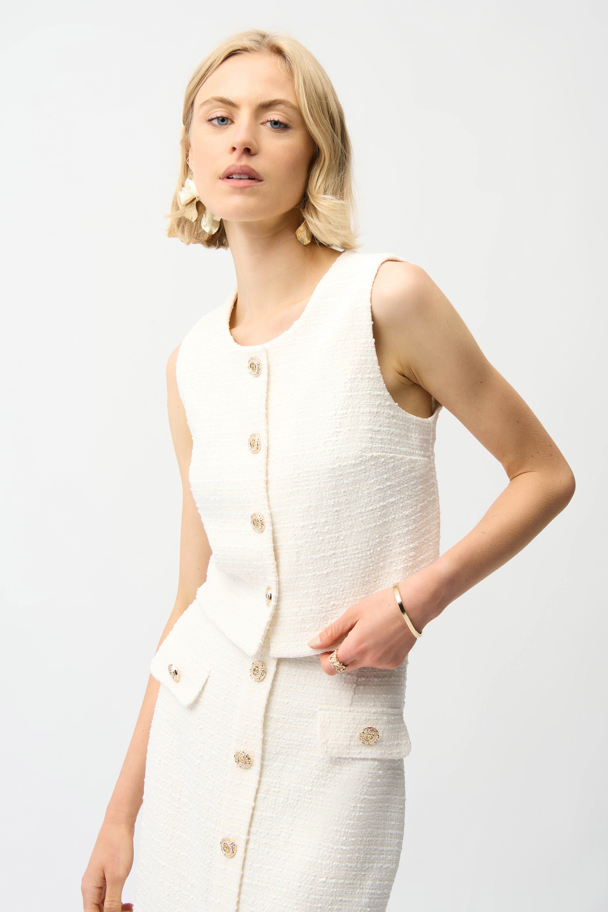 Woman wearing a white textured sleeveless top and skirt set on a plain background