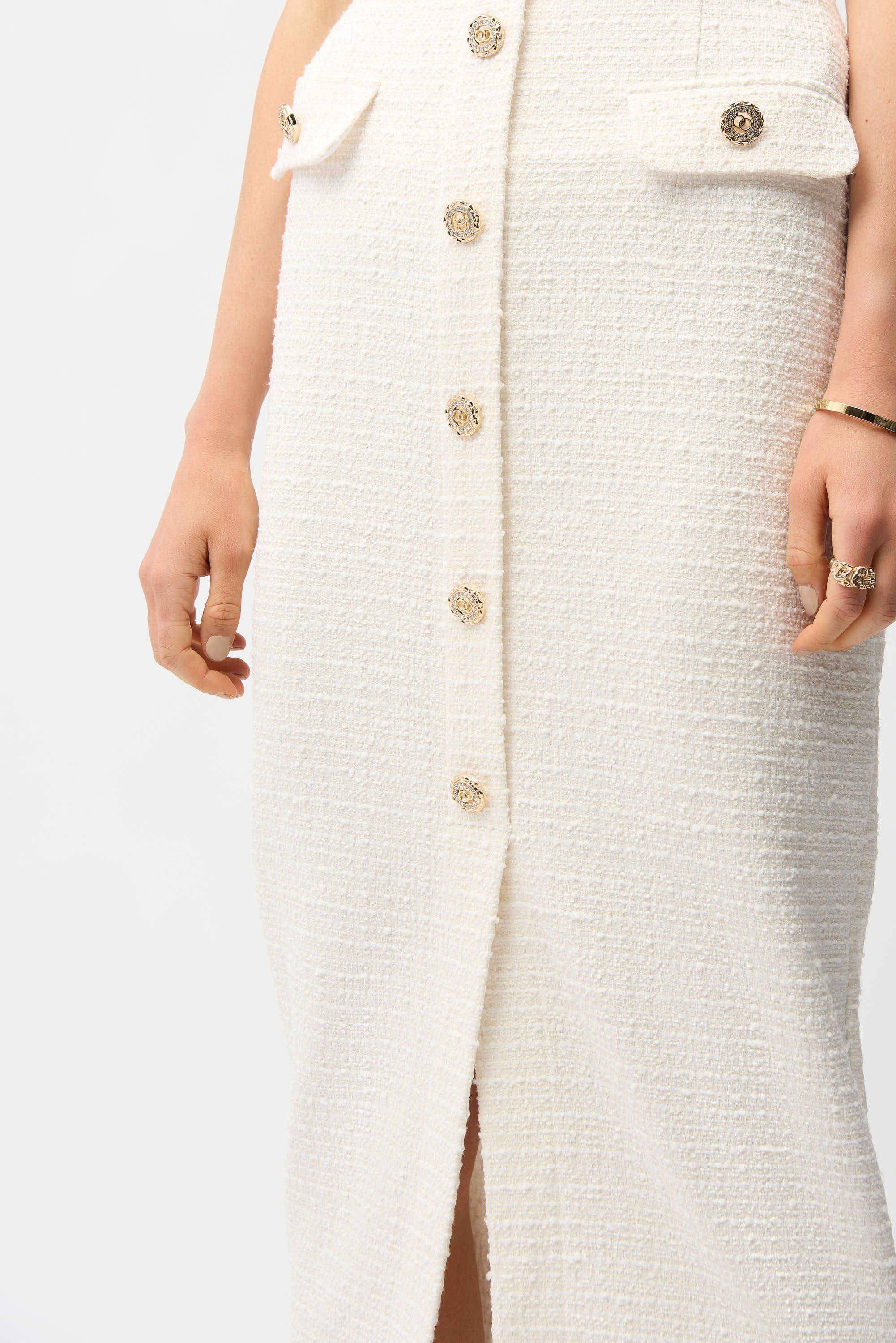 White textured dress with gold buttons on a plain background