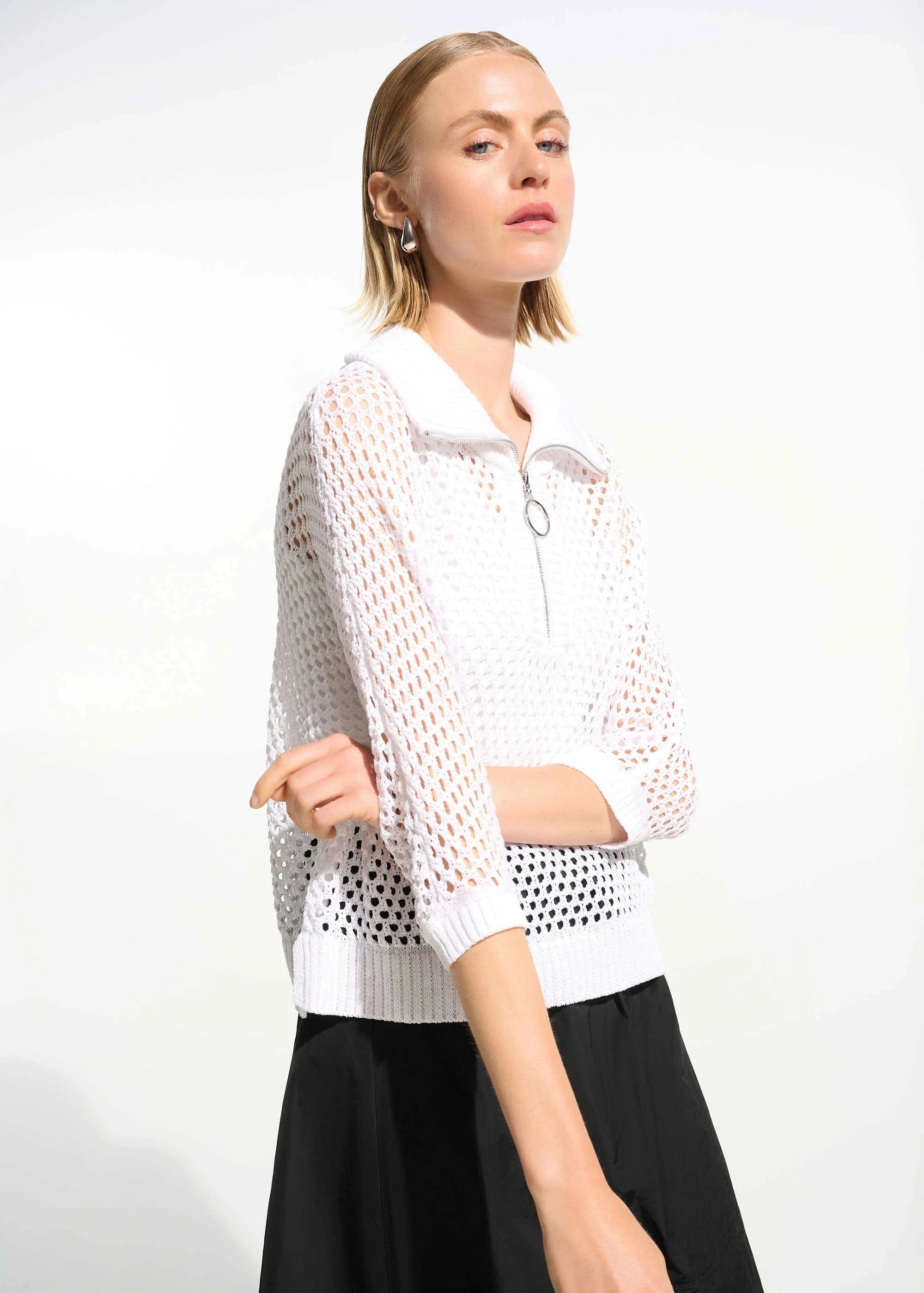 Woman wearing a white mesh top and black pants on a white background